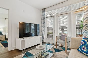 A living room with a couch and a glass coffee table and a television